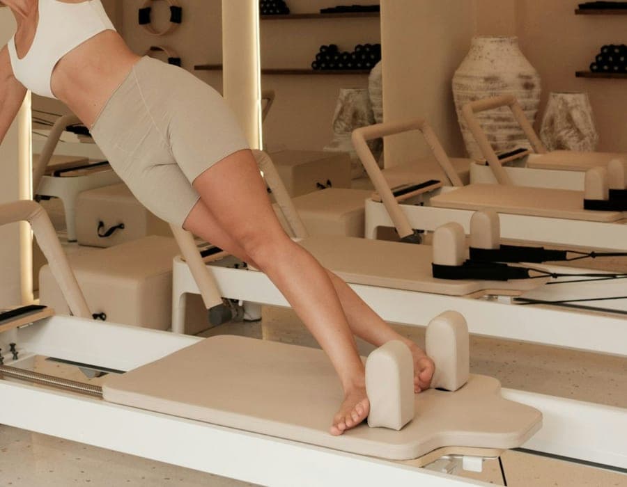 Mulher praticando pilates em um aparelho dentro do estúdio