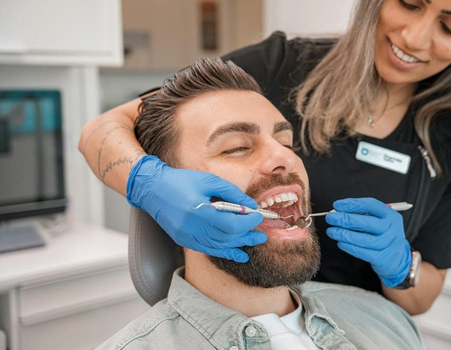 Paciente recebendo limpeza dos dentes por uma profissional de odontologia