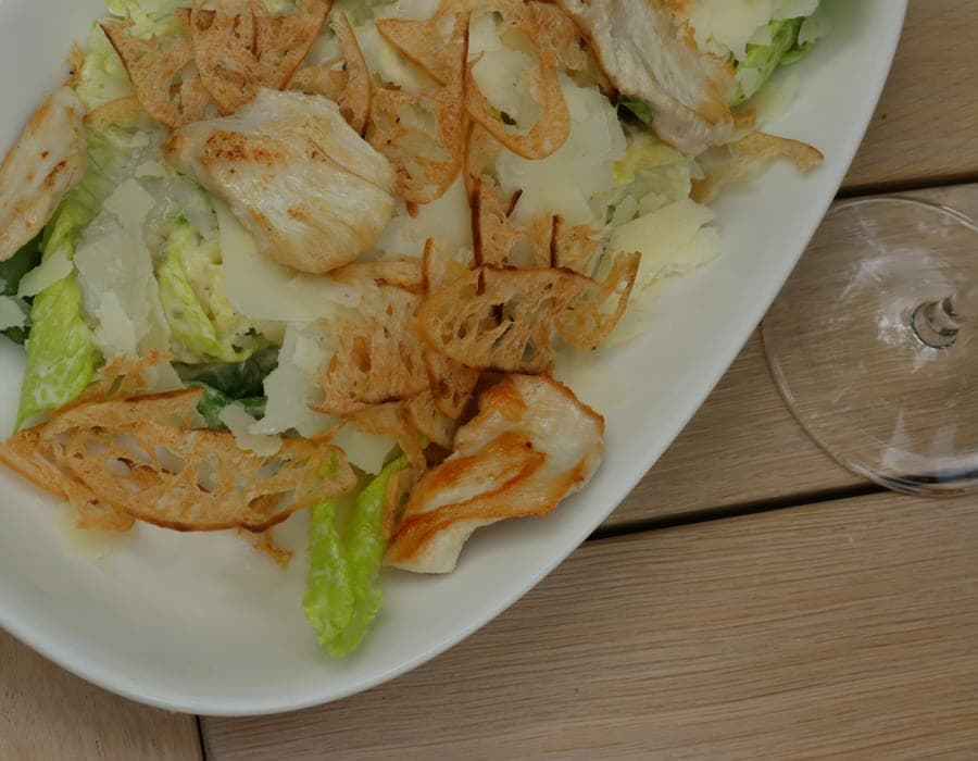 Salada com folhas, frango grelhado, lascas de queijo e crocantes de pão